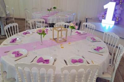 Table ronde avec verres vides, assiettes empilées, couverts, serviettes et desserts en arrière-plan.