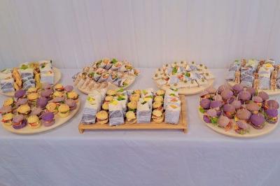 Table ronde avec verres vides, assiettes empilées, couverts, serviettes et desserts en arrière-plan.