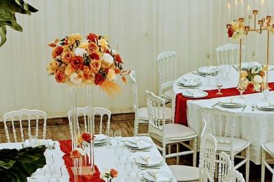 Table ronde avec verres vides, assiettes empilées, couverts, serviettes et desserts en arrière-plan.