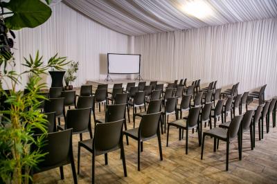 Salle de réception décorée avec des tables rondes dressées, un écran de projection et un éclairage coloré.