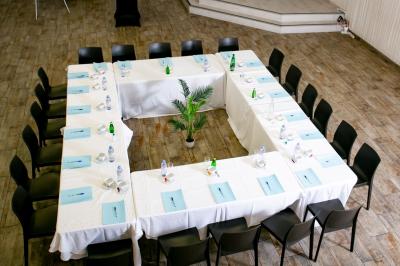 Salle de réception décorée avec des tables rondes dressées, un écran de projection et un éclairage coloré.