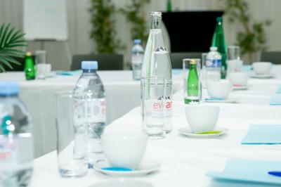 Salle de réception décorée avec des tables rondes dressées, un écran de projection et un éclairage coloré.