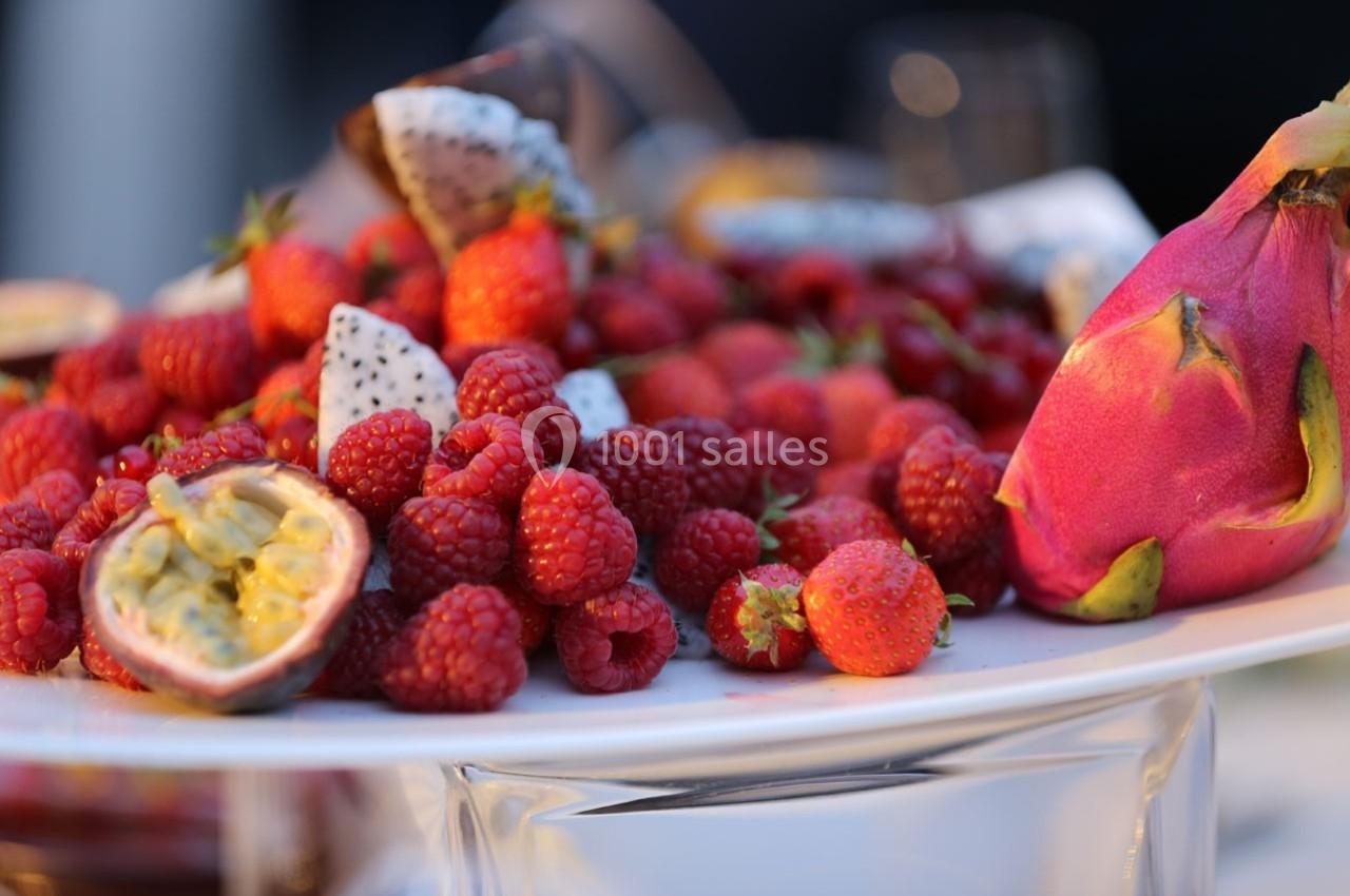 Assiette garnie de fruits frais, incluant des framboises, fraises, fruits de la passion et pitayas.