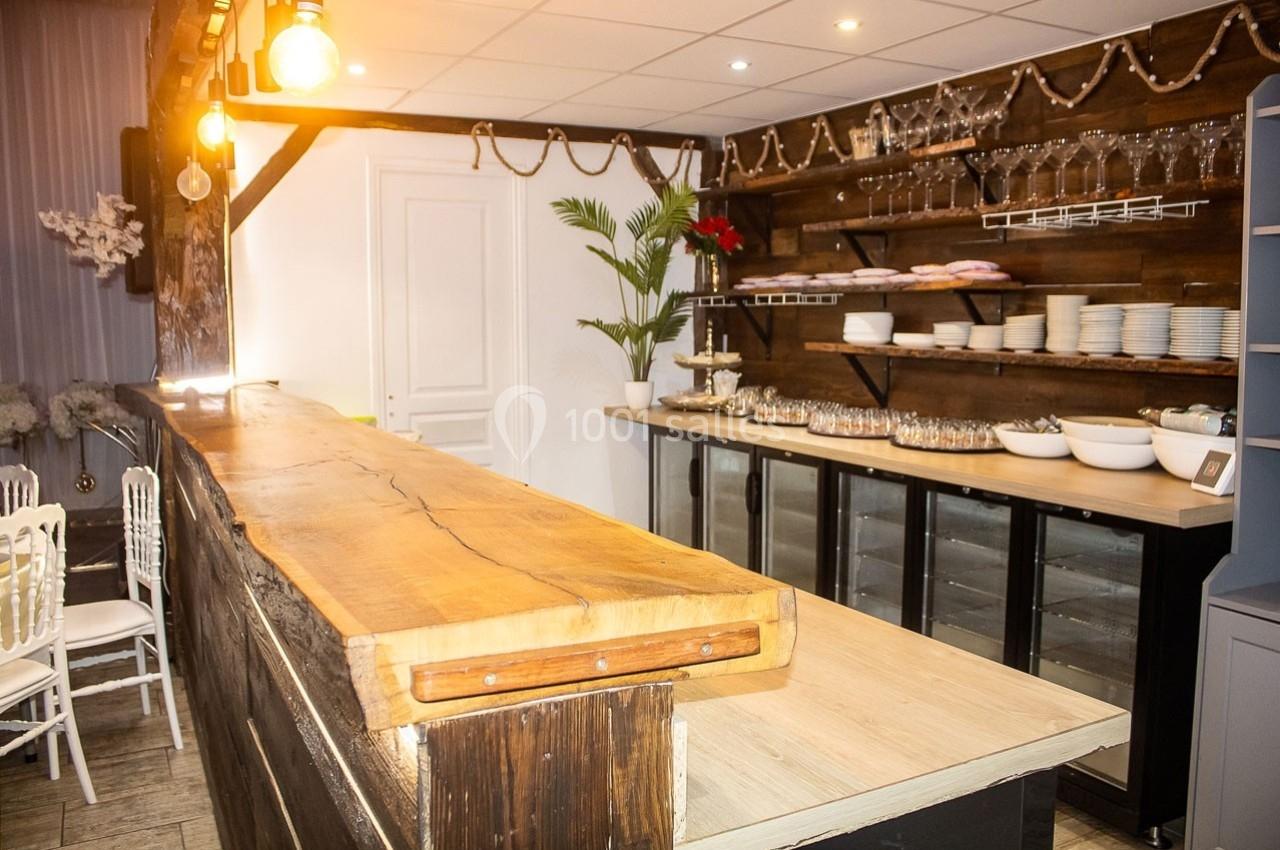 Comptoir en bois massif dans une salle décorée avec des étagères garnies de vaisselle et des guirlandes lumineuses.