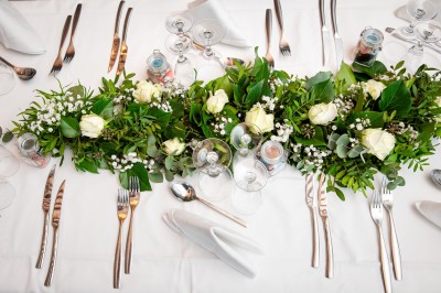 Comptoirs en bois avec décorations florales, installés en extérieur sous un ciel dégagé près de bâtiments modernes.