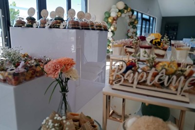 Comptoirs en bois avec décorations florales, installés en extérieur sous un ciel dégagé près de bâtiments modernes.