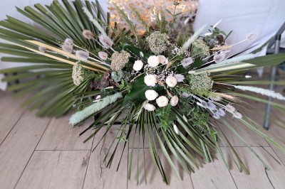 Comptoirs en bois avec décorations florales, installés en extérieur sous un ciel dégagé près de bâtiments modernes.