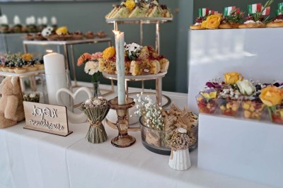 Comptoirs en bois avec décorations florales, installés en extérieur sous un ciel dégagé près de bâtiments modernes.