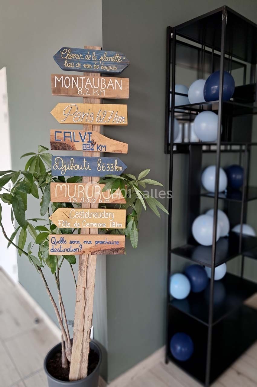 Panneau directionnel coloré indiquant des distances vers différentes villes, placé à côté d'une plante et d'une étagère avec…