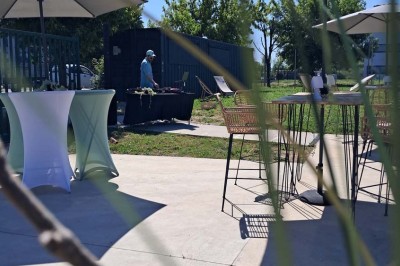 Comptoirs en bois avec décorations florales, installés en extérieur sous un ciel dégagé près de bâtiments modernes.