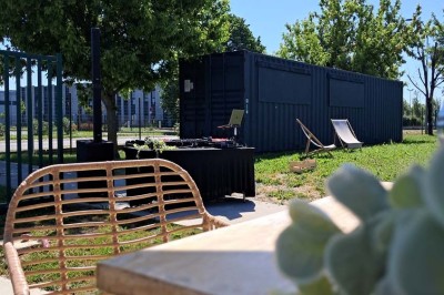 Comptoirs en bois avec décorations florales, installés en extérieur sous un ciel dégagé près de bâtiments modernes.