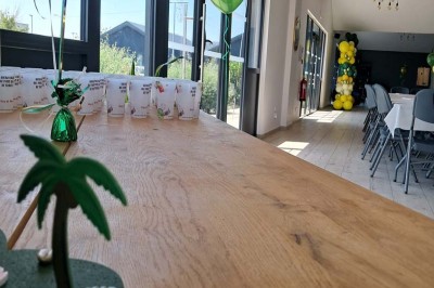 Comptoirs en bois avec décorations florales, installés en extérieur sous un ciel dégagé près de bâtiments modernes.