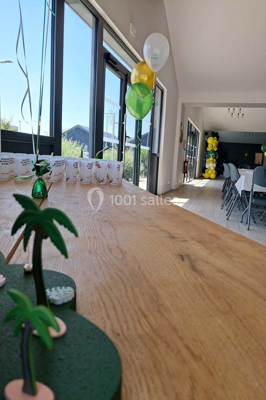 Décoration tropicale sur une table en bois dans une salle lumineuse, avec ballons et chaises en arrière-plan.