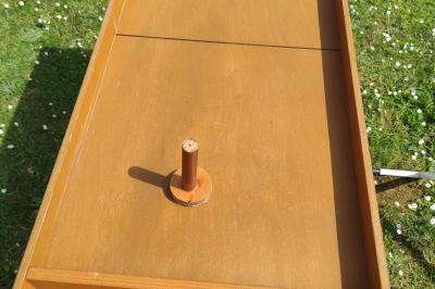 Planche de jeu de lancer de sacs colorée posée sur une pelouse, avec des sacs verts et jaunes dispersés autour.