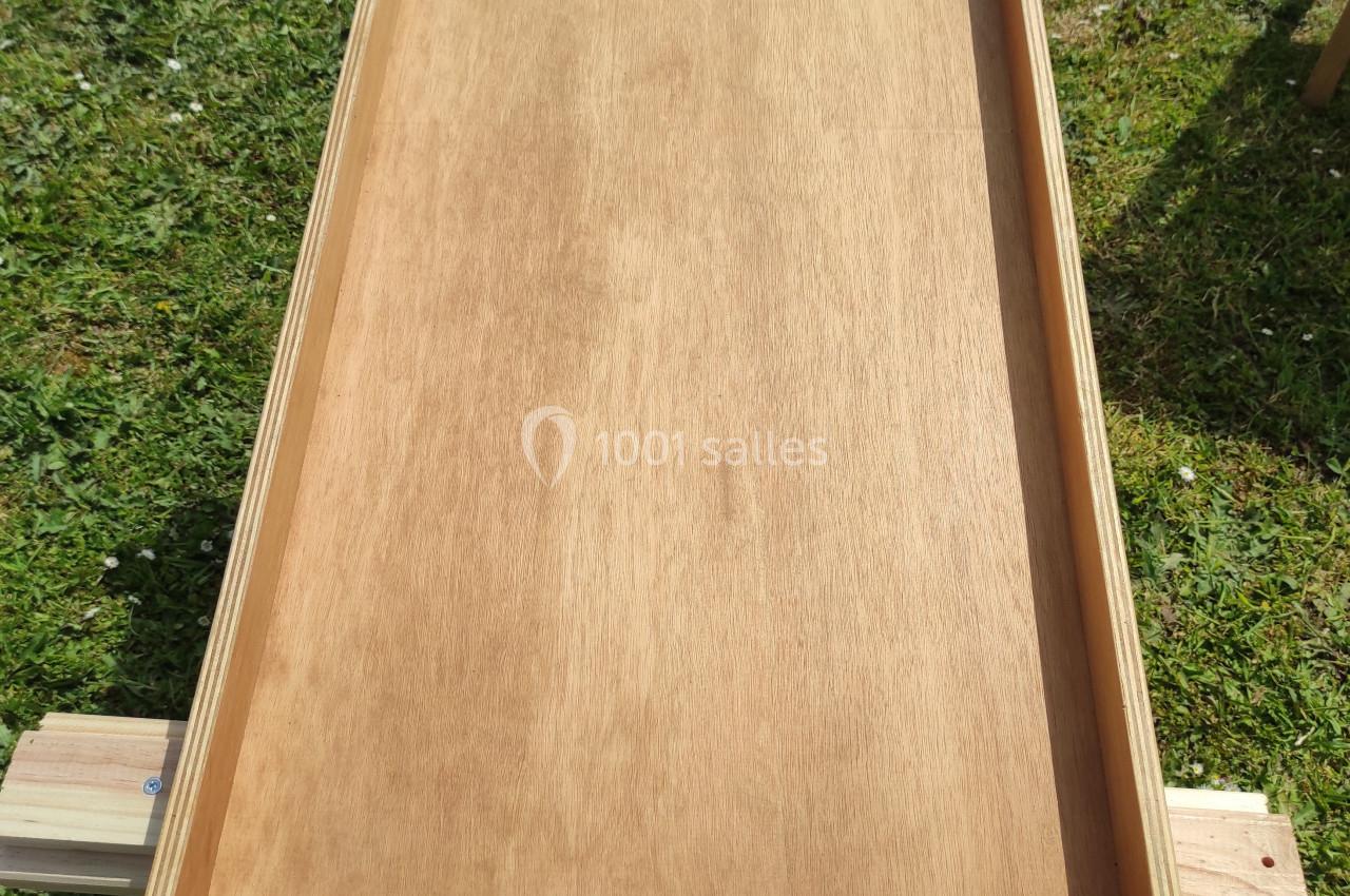 Jeu de billard hollandais en bois avec des boules blanches alignées en bas, posé sur une pelouse.