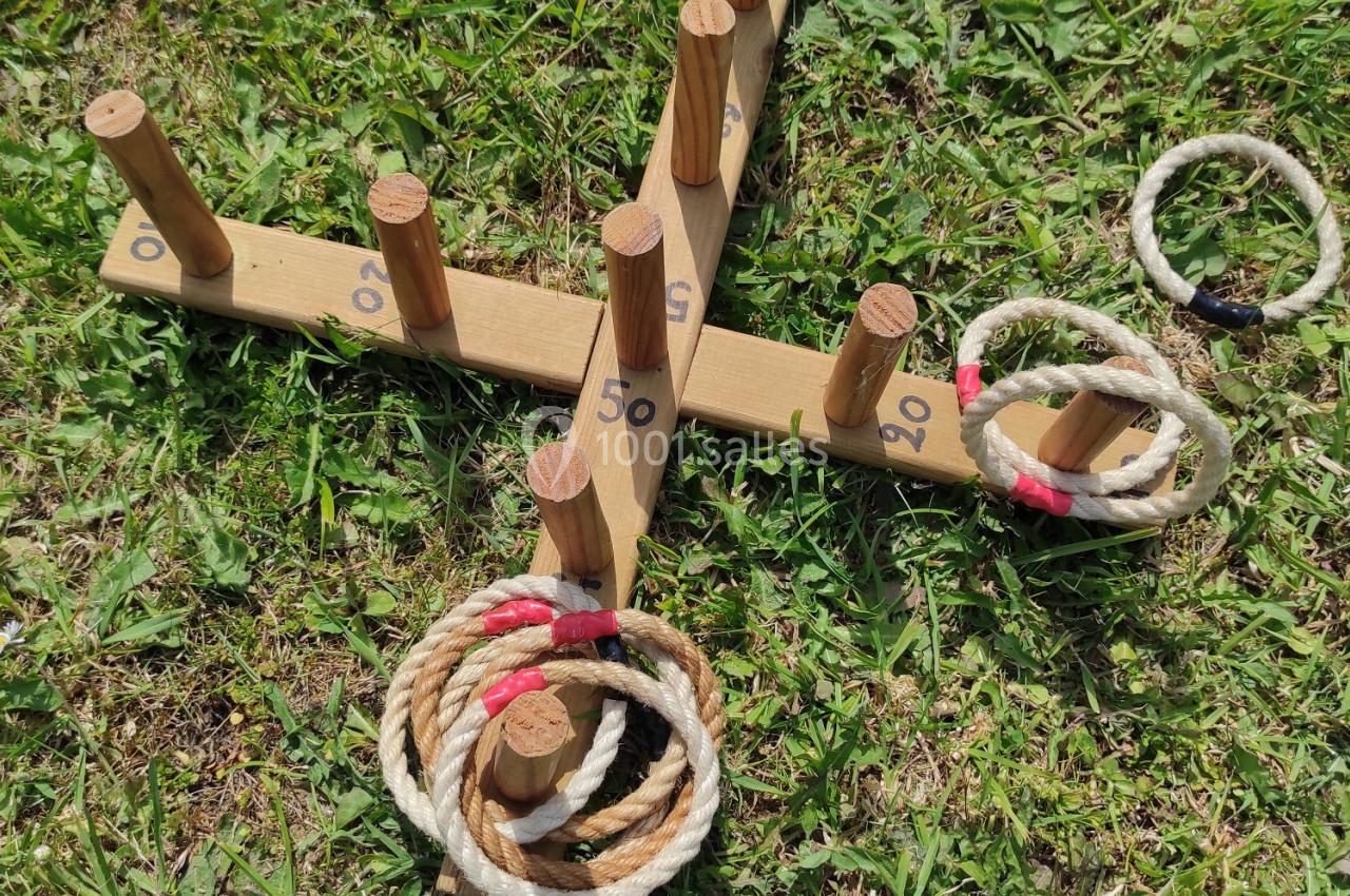 Jeu de lancer d'anneaux en corde sur une structure en bois avec des points marqués, posé sur une pelouse.