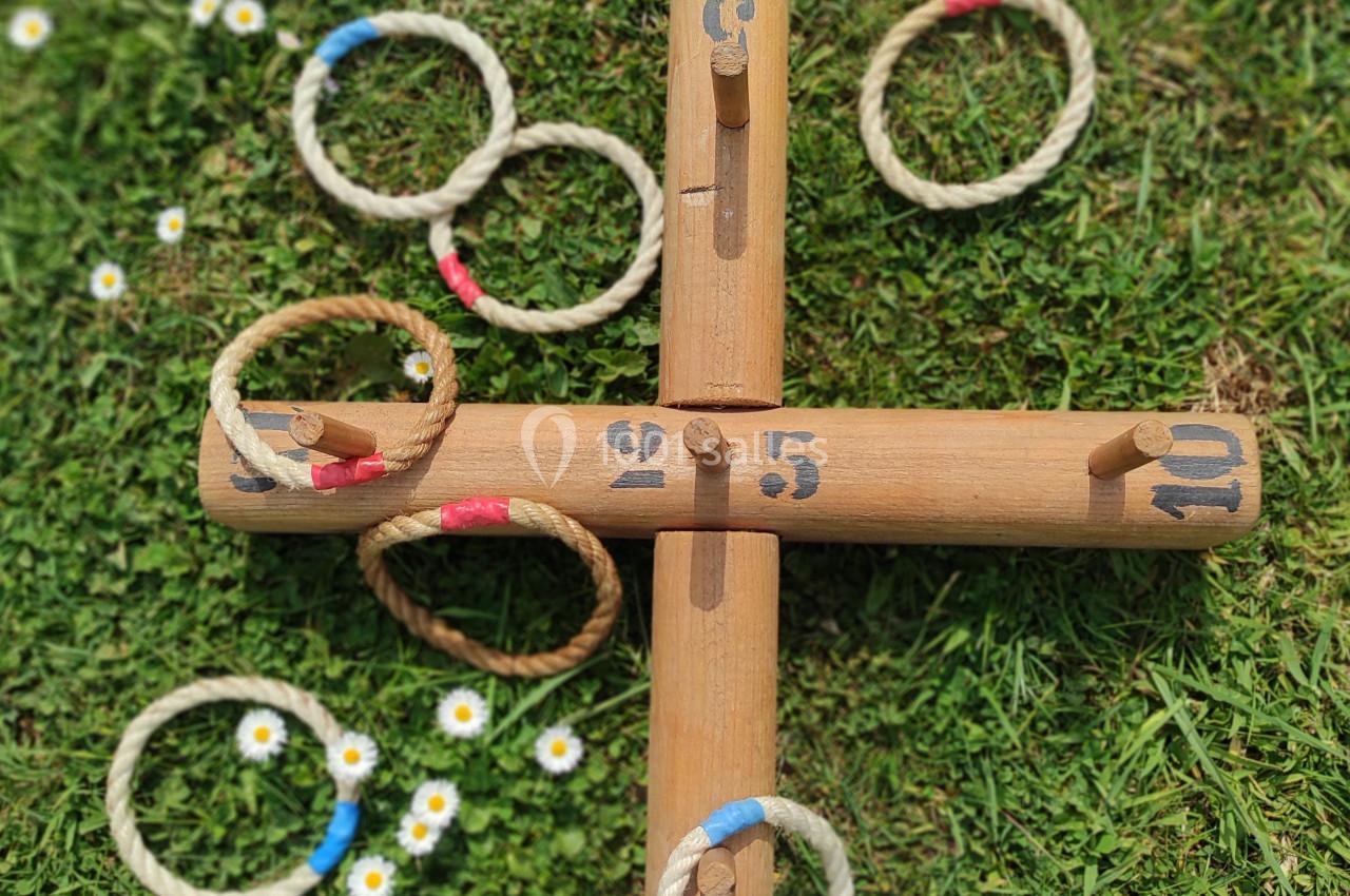 Jeu de lancer d'anneaux en corde sur une structure en bois, posé sur une pelouse avec des pâquerettes.