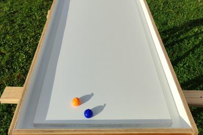 Disque en bois avec des cercles numérotés et des pions en bois disposés sur différentes zones de points.