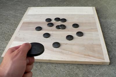 Disque en bois avec des cercles numérotés et des pions en bois disposés sur différentes zones de points.
