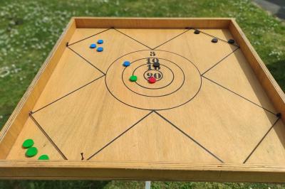 Disque en bois avec des cercles numérotés et des pions en bois disposés sur différentes zones de points.