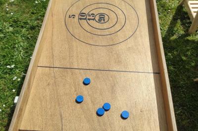 Disque en bois avec des cercles numérotés et des pions en bois disposés sur différentes zones de points.