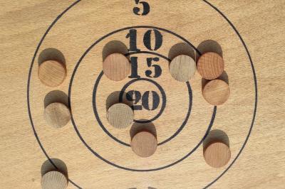 Disque en bois avec des cercles numérotés et des pions en bois disposés sur différentes zones de points.
