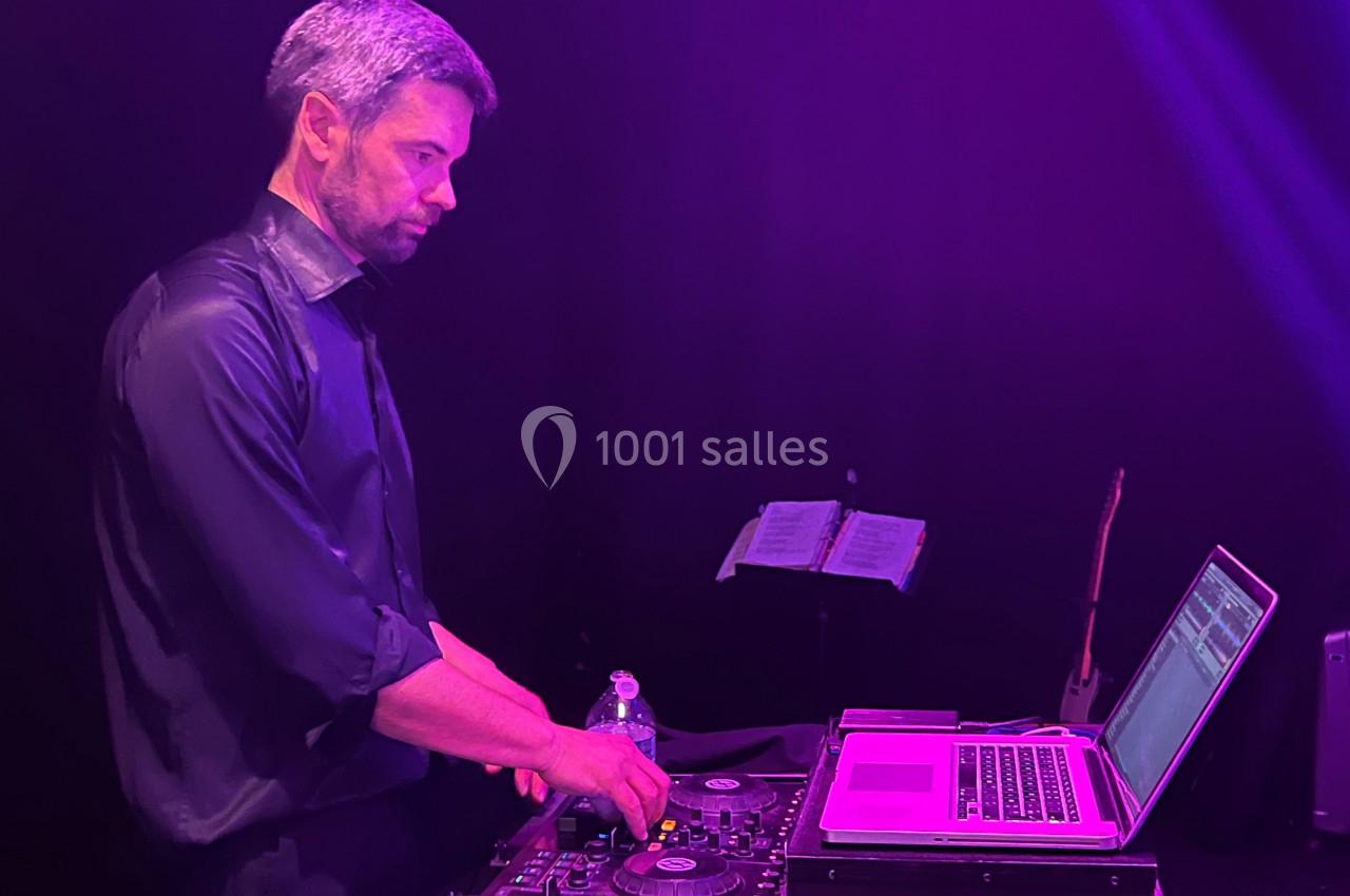 Un homme utilise une table de mixage et un ordinateur portable sous un éclairage violet.