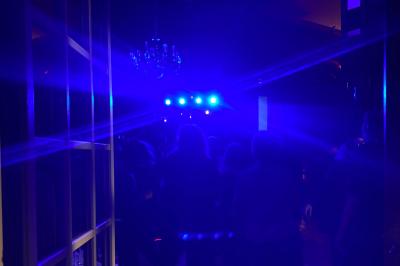 Des serveurs en tenue formelle apportent des plateaux avec des desserts ornés de cierges magiques dans une ambiance festive.