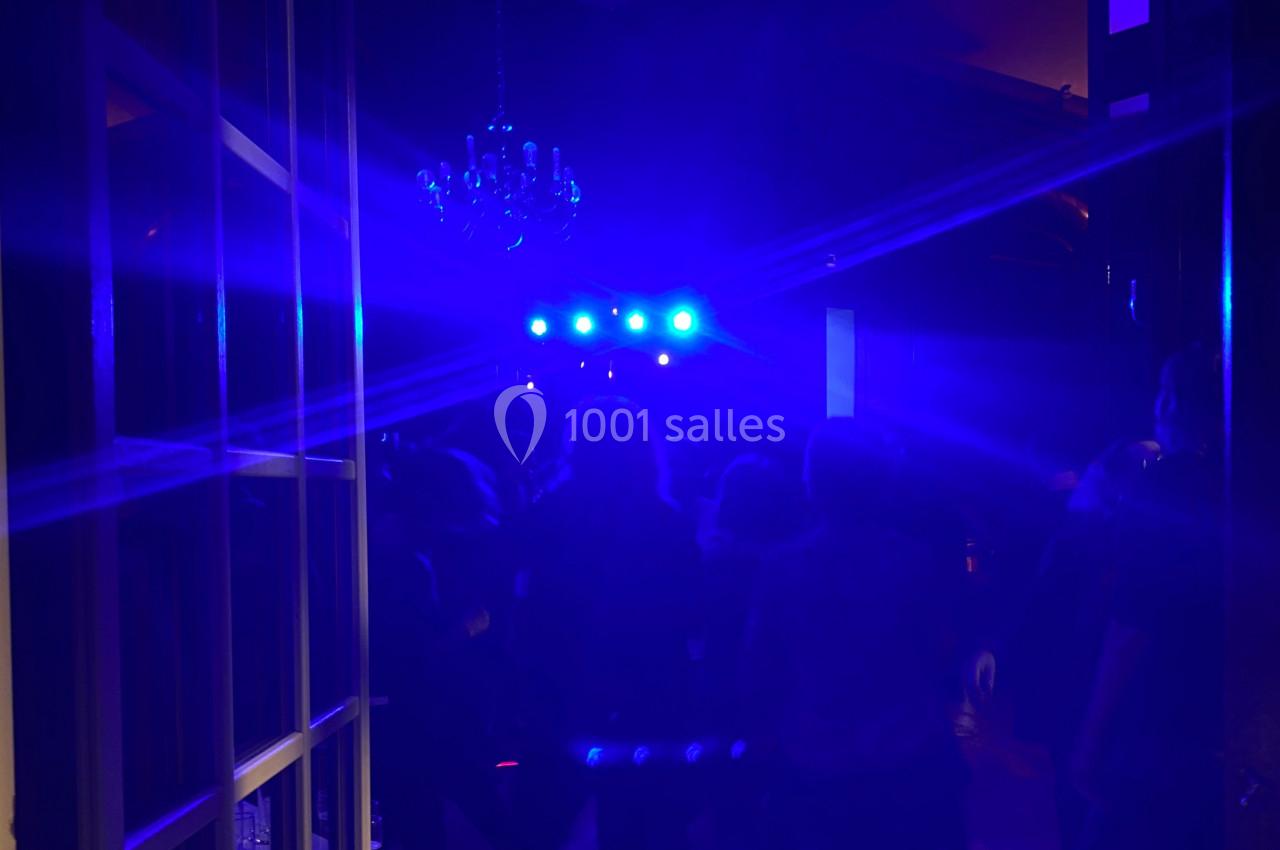 Foule dans une salle sombre éclairée par des lumières bleues vives, avec un lustre visible au plafond.