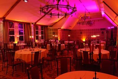 Des serveurs en tenue formelle apportent des plateaux avec des desserts ornés de cierges magiques dans une ambiance festive.