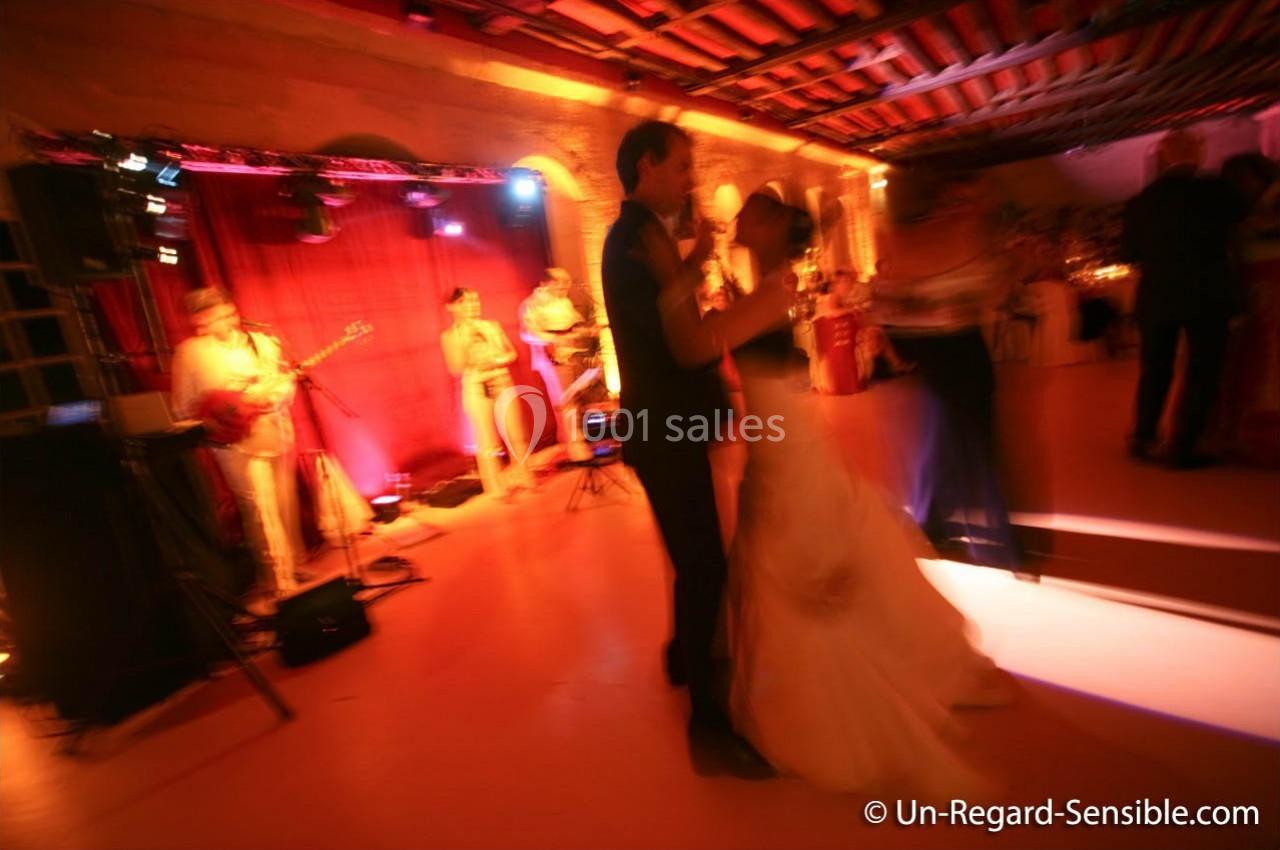 Un couple danse dans une salle éclairée de lumières chaudes, avec un groupe de musiciens en arrière-plan.
