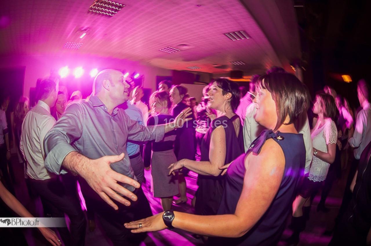 Des personnes dansent et s'amusent sur une piste éclairée par des lumières colorées dans une ambiance festive.