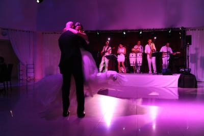 Un couple danse sous des lumières violettes tandis qu'un groupe joue de la musique sur une scène en arrière-plan.