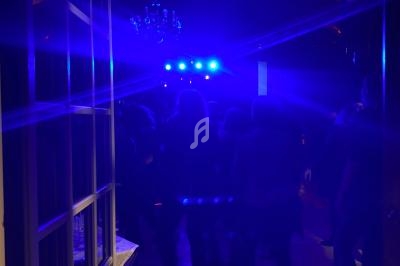 Groupe de personnes debout dans une pièce sombre éclairée par des lumières bleues vives au fond.