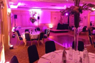 Salle de réception avec tables rondes dressées, éclairage tamisé et piste de danse en bois.