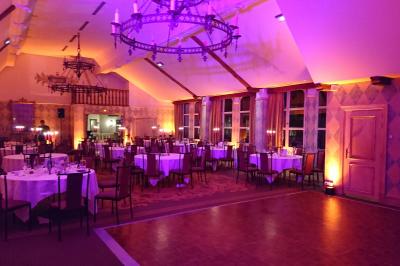 Salle de réception décorée avec des tables rondes, des chandeliers allumés et un éclairage tamisé aux tons chauds.