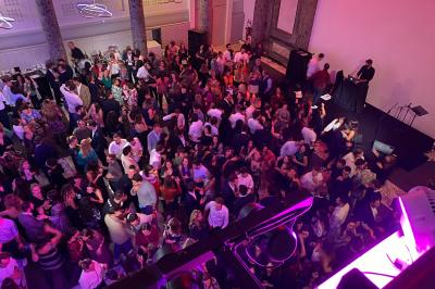 Salle de réception décorée avec des tables rondes, des chandeliers allumés et un éclairage tamisé aux tons chauds.