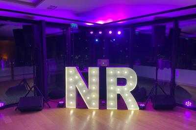 Salle de réception décorée avec des tables rondes, des chandeliers allumés et un éclairage tamisé aux tons chauds.