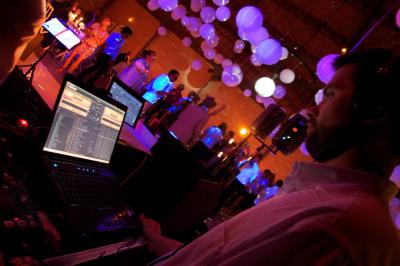 Salle de réception décorée avec des tables rondes, des chandeliers allumés et un éclairage tamisé aux tons chauds.