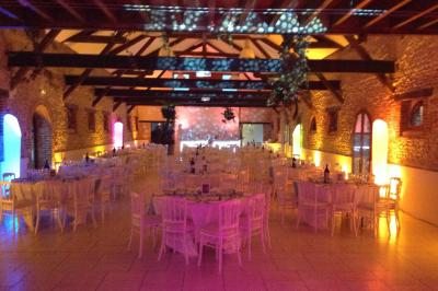 Salle de réception décorée avec des tables rondes, des chandeliers allumés et un éclairage tamisé aux tons chauds.