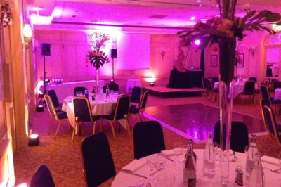 Salle de réception décorée avec des tables rondes, des chandeliers allumés et un éclairage tamisé aux tons chauds.