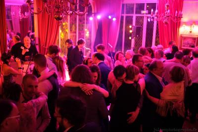 Salle de réception décorée avec des tables rondes, des chandeliers allumés et un éclairage tamisé aux tons chauds.