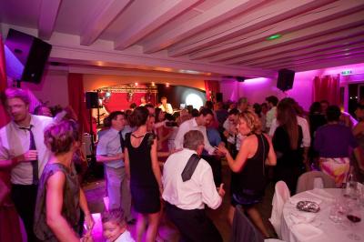 Salle de réception décorée avec des tables rondes, des chandeliers allumés et un éclairage tamisé aux tons chauds.