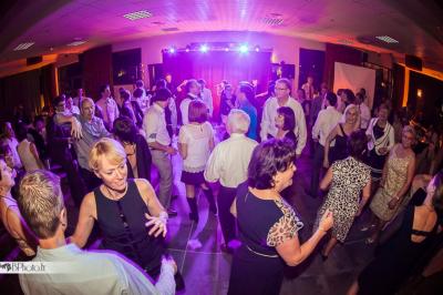 Salle de réception décorée avec des tables rondes, des chandeliers allumés et un éclairage tamisé aux tons chauds.