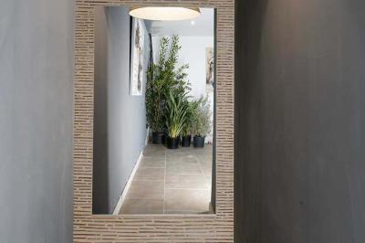 Maison en pierre avec toit en ardoise, entourée d'arbres et de végétation, sous un ciel partiellement nuageux.