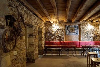 Maison en pierre avec toit en ardoise, entourée d'arbres et de végétation, sous un ciel partiellement nuageux.