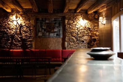 Maison en pierre avec toit en ardoise, entourée d'arbres et de végétation, sous un ciel partiellement nuageux.