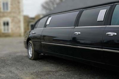 Maison en pierre avec toit en ardoise, entourée d'arbres et de végétation, sous un ciel partiellement nuageux.