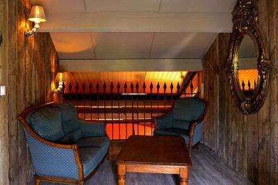 Maison en pierre avec toit en ardoise, entourée d'arbres et de végétation, sous un ciel partiellement nuageux.