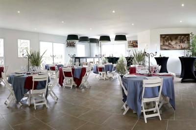 Maison en pierre avec toit en ardoise, entourée d'arbres et de végétation, sous un ciel partiellement nuageux.